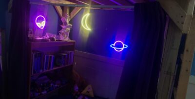 three neon signs illuminating a nook underneath my loft that has curtains surrounding it