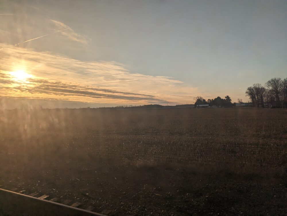 sunrise through clouds over an empty field