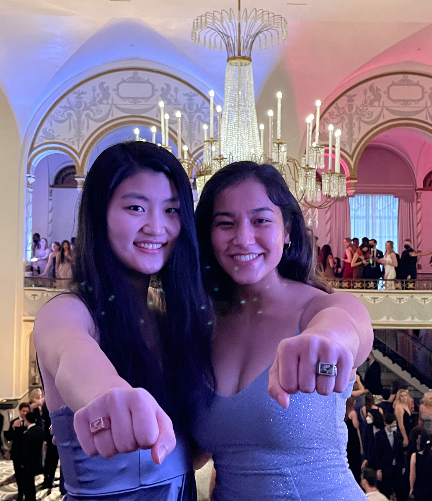 two girls in dresses holding their fists out to show off their rings